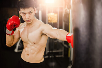 Fitness concept, Asian men boxers punching punching bags in a training facility.
