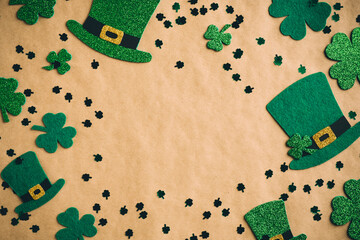 St Patrick's Day banner design. Irish leprechaun hats and shamrock clover leaves on kraft paper background with copy space. Happy Saint Patricks Day concept. Flat lay, top view.