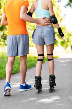 fitness, sport and healthy lifestyle concept - happy couple with roller skates riding outdoors