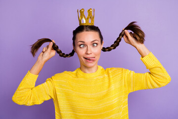 Portrait of excited girl hands playing with hair tails squint eyes tongue out isolated on purple...