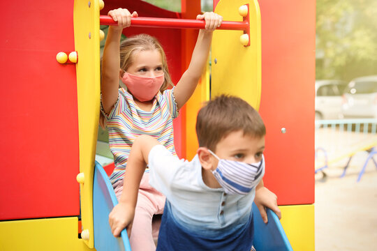 Little Children With Medical Face Masks On Playground During Covid-19 Quarantine
