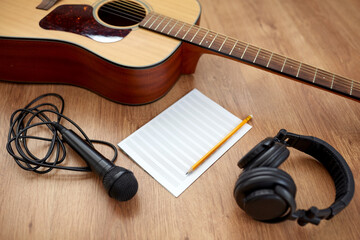 composing and music writing concept - close up of acoustic guitar with music book, microphone and...
