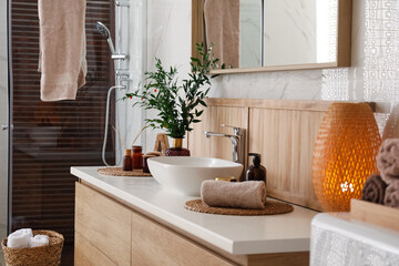 Vase with beautiful branches, candles and toiletries near vessel sink in bathroom. Interior design