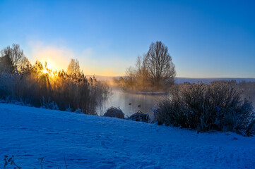 sunrise and mist over small pond i Kumla lakepark Sweden