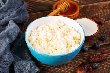 Cottage cheese with honey and berries on wooden background. Light vegetarian breakfast.
