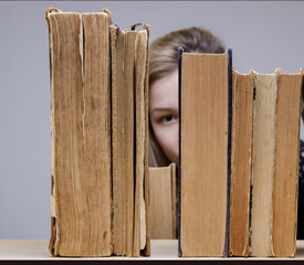 young woman picks up or puts an old book on the shelf. library. selective focus. 
