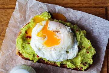Avocado toast with poached egg on wooden board, top view. Breakfast concept.