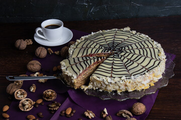 Delicious festive cut esterhazy cake with nuts, cream and chocolate on a dark background close-up