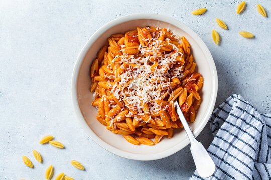 Gnocchetti sardi pasta in tomato sauce with cheese, gray background. Italian pasta concept