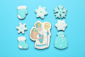 Tasty gingerbread cookies on light blue background, flat lay. St. Nicholas Day celebration