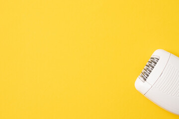 Compact electric epilator on yellow background. Free space for text.