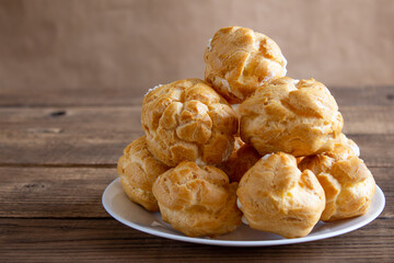 Eclairs on white plate on a wodden background. eclairs with cream.