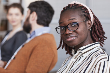 Close up portrait of young African-American woman wearing glasses and looking at camera while...