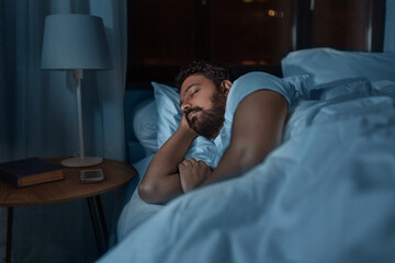 people, bedtime and rest concept - indian man sleeping in bed at home at night