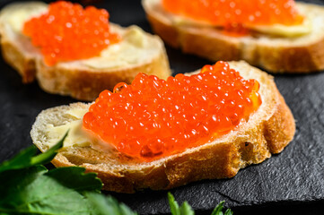 Sandwiches with salmon red caviar. Black background. Top view