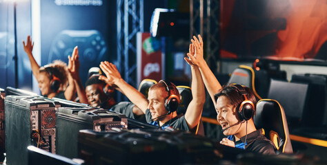 Celebrating success. Team of happy proffesional cyber sport gamers giving high five to each other...