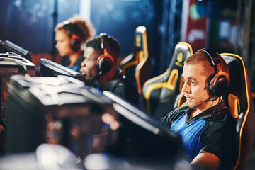 Focused on game. Male cybersport gamer wearing headphones playing online video games, participating...