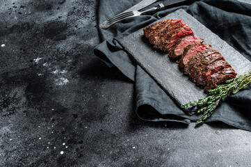 Grilled roasting rare sliced skirt, machete steak. Marble meat beef. Black background. Top view....