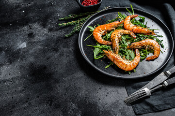 Salad with grilled giant tiger shrimps, prawns and arugula. Black background. Top view. Copy space