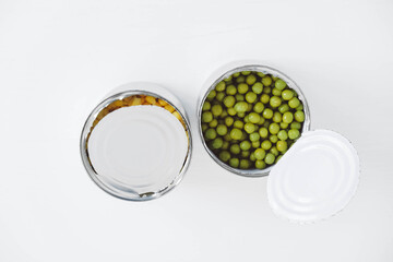 Two open cans with corn and peas on a white background. Top view. Copy, empty space for text