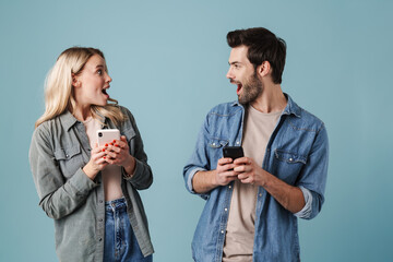 Young surprised man and woman exclaiming while using mobile phones