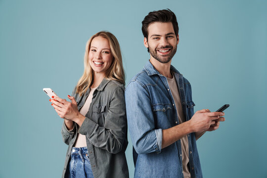 Young happy man and woman smiling and using mobile phones