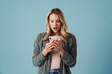Shocked beautiful blonde girl exclaiming while using mobile phone