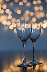 Empty glasses of wine on glass table with bokeh background close up. New Year, Christmas mood. Greeting card. Party and holiday celebration concept.