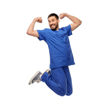 Healthcare, Profession And Medicine Concept - Happy Smiling Doctor Or Male Nurse In Blue Uniform Jumping In Air Over White Background