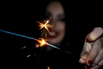 Female hand holding a burning sparkler in the night