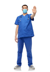 healthcare, profession and medicine concept - doctor or male nurse in blue uniform, face protective medical mask for protection from virus disease and gloves showing stop gesture over white background