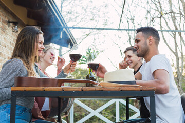 Outdoor photography of young people toasting with their wine glasses on the rooftop - Couple of friends enjoying a meal outdoors.