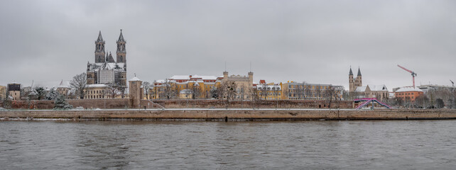 Panoramic view over Magdeburg historical downtown in Winter with icy trees and snow during foggy day and dramatic sky, Germany.