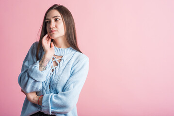 Thoughtful brunette girl in the studio on a pink background with copy space