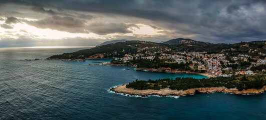 Aerial view over Votsi beach (Paralia Votsi) and the picturesque port with traditional wooden fishing boats in Alonnisos island during Winter period in Sporades, Greece