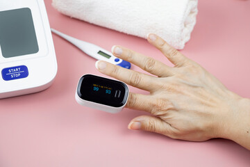 a woman's hand with a pulse oximeter on her finger to measure medical indications