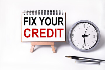 fix your credit, text on white notepad paper. notepad on stand on white background