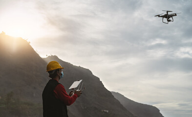 Male engineer doing inspection using drone while wearing face mask to avoid corona virus spreading - Technology and industrial concept