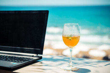 Working with laptop and drinking cocktail by the beach
