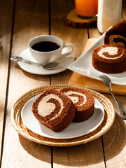 Chocolate cake roll with cup of coffee orange juice and milk on wooden table, Breakfast set concept.