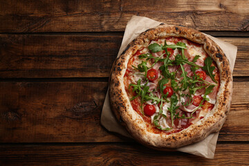 Tasty pizza with meat and arugula on wooden table, top view. Space for text