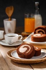 Chocolate cake roll with cup of coffee orange juice and milk on wooden table, Breakfast set concept.