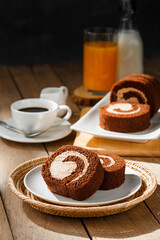 Chocolate cake roll with cup of coffee orange juice and milk on wooden table, Breakfast set concept.