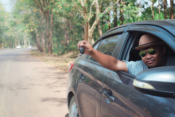 Young asian man holding key while sitting in old car,Car driver showing automobile key, purchase and rent of transport, test-drive