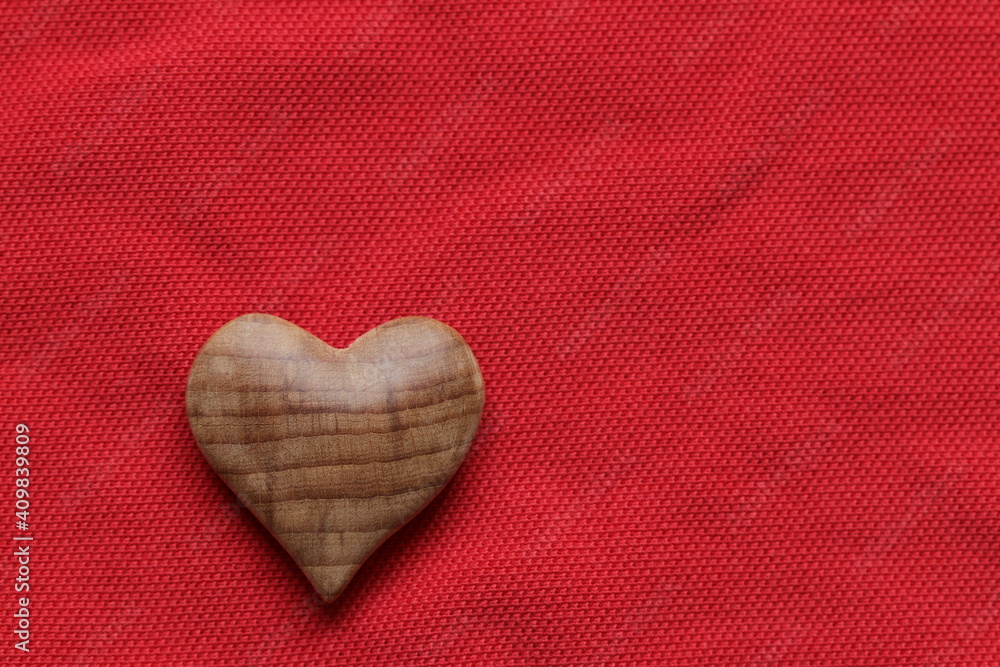 Wall mural valentine's day, wooden heart on a red fabric background.