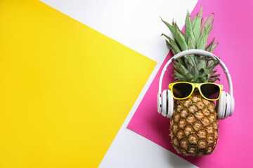 Top view of pineapple with headphones and sunglasses on color background, space for text. Creative...