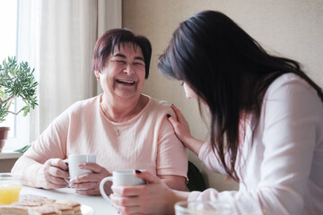 A daughter visits her grandmother - An elderly woman and a young woman drink tea and socialize -...