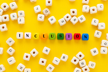 Inclusion text yellow background. Inclusive social concept. Wooden blocks, top view.