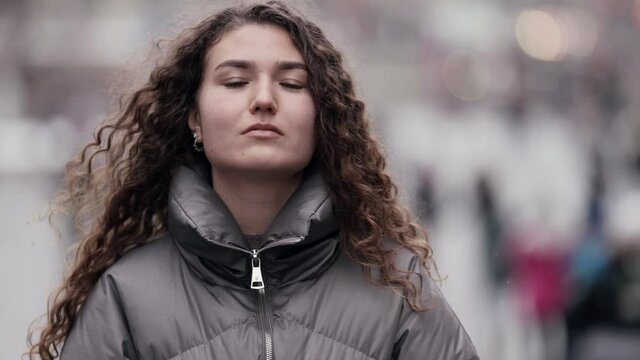 confident young lady is walking alone in megapolis at winter day, medium portrait, emancipation
