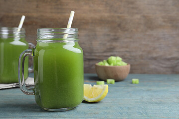 Fresh celery juice and lemon slice on blue wooden table, closeup. Space for text